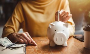 Woman puting money in piggy bank