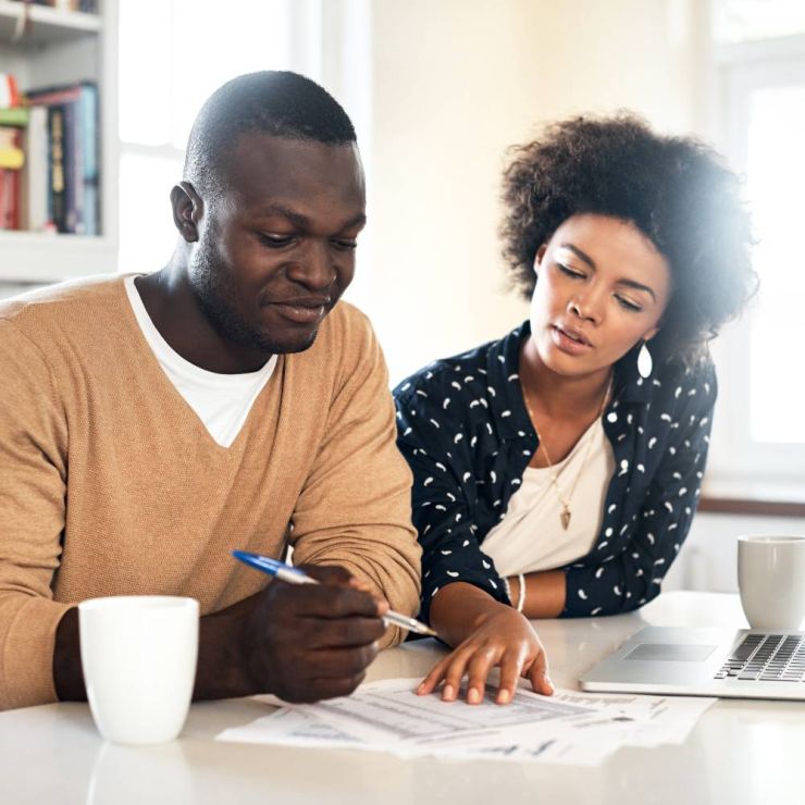 Man and woman sitting at kitchen counter, reviewing financial documents